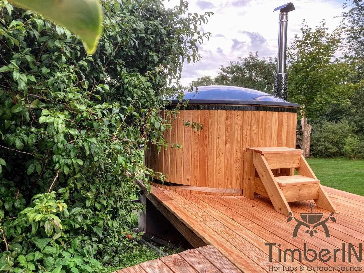 Types of Wood for Hot Tubs & Outdoor Saunas 3 Round TimberIN hot tub with warm golden larch cladding, wooden steps and a dark insulated cover in a garden