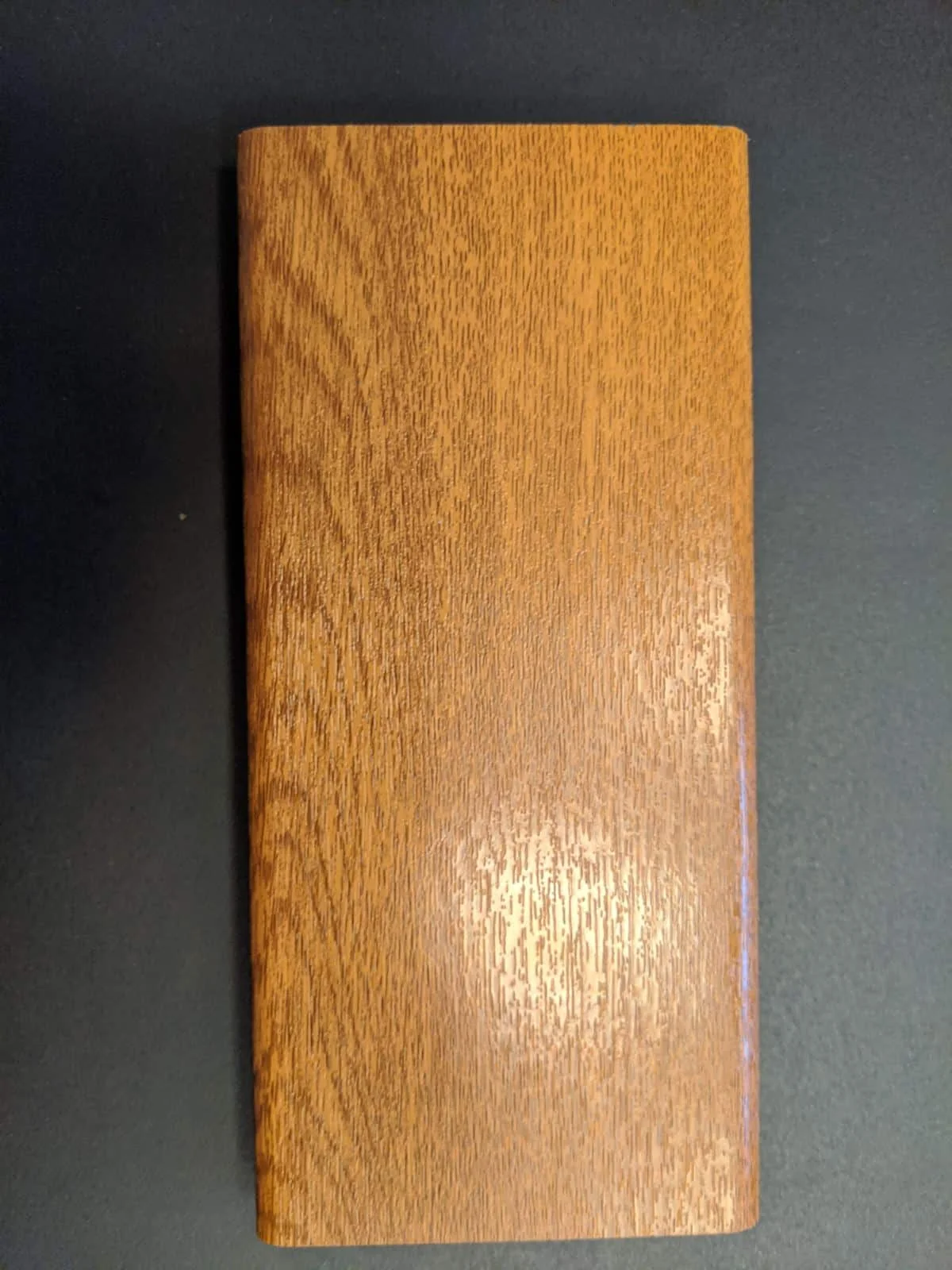 Types of Wood for Hot Tubs & Outdoor Saunas 5 Oiled oak sample board with dense golden brown grain displayed against a dark background