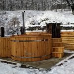 4 Person Hot Tubs 9 Wood Fired Wooden Jacuzzi with timber staves, external wood stove, chimney and steps in a winter garden.