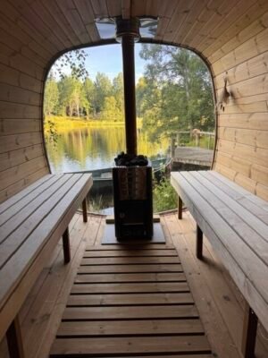 Interior of the TimberIN Nordic Square Mobile Sauna with wooden benches and wood-burning stove beside a lake