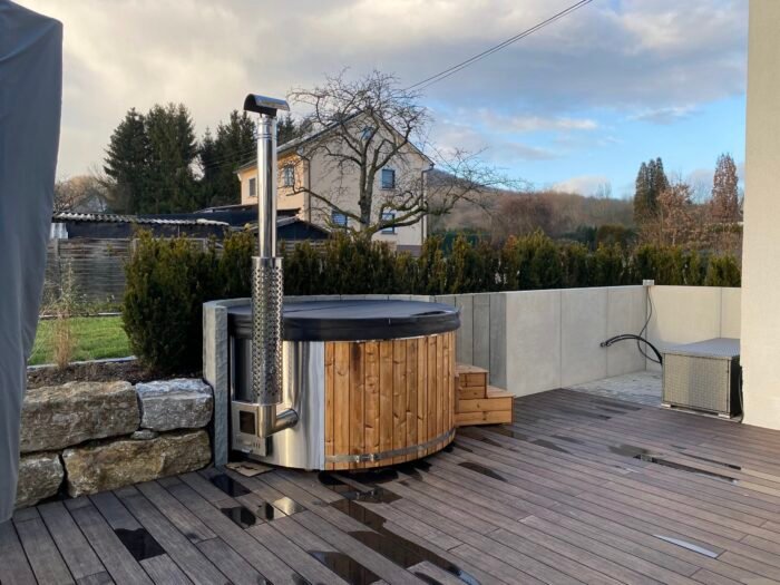 Wood fired wooden hot tub in UK garden with stainless steel stove