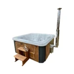 4 Person Hot Tubs 16 TimberIN Nordic Square™ Acrylic Hot Tub – External or Integrated Wood Stove (Luxury Marble Edition) – square luxury hot tub with white marble-effect acrylic liner, timber and dark-panel cladding, wooden steps, external stove and tall chimney on a white background.