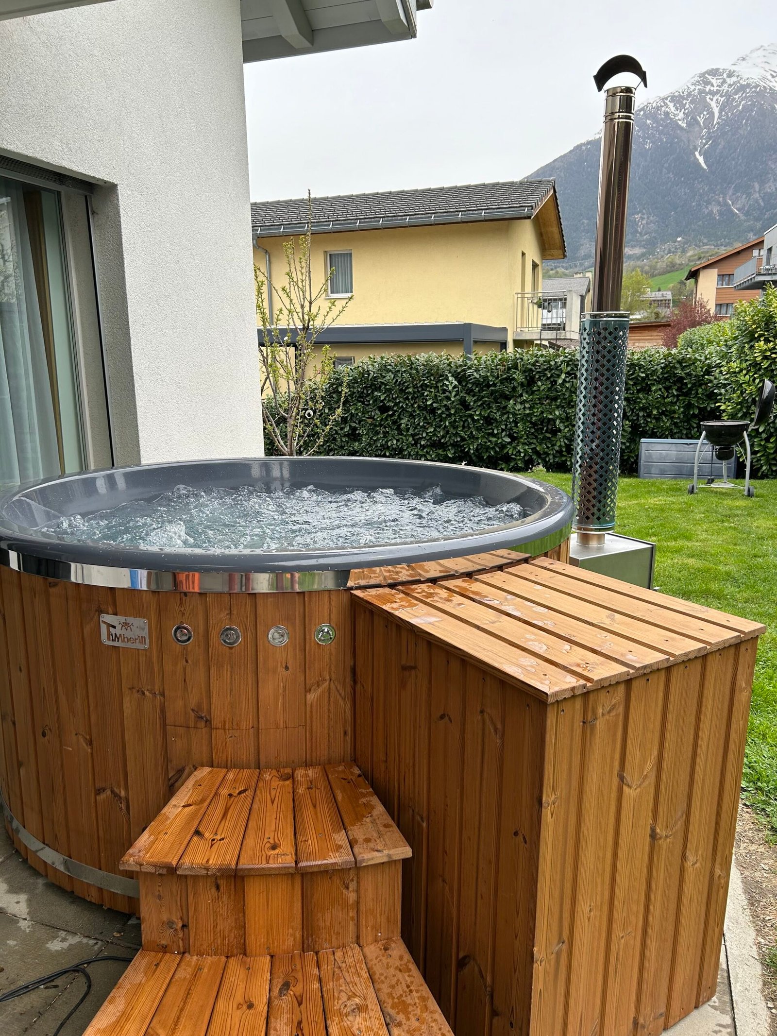 Hot Tubs with Jets 1 Round timber-clad hot tub with moving water, wooden steps and an external stove