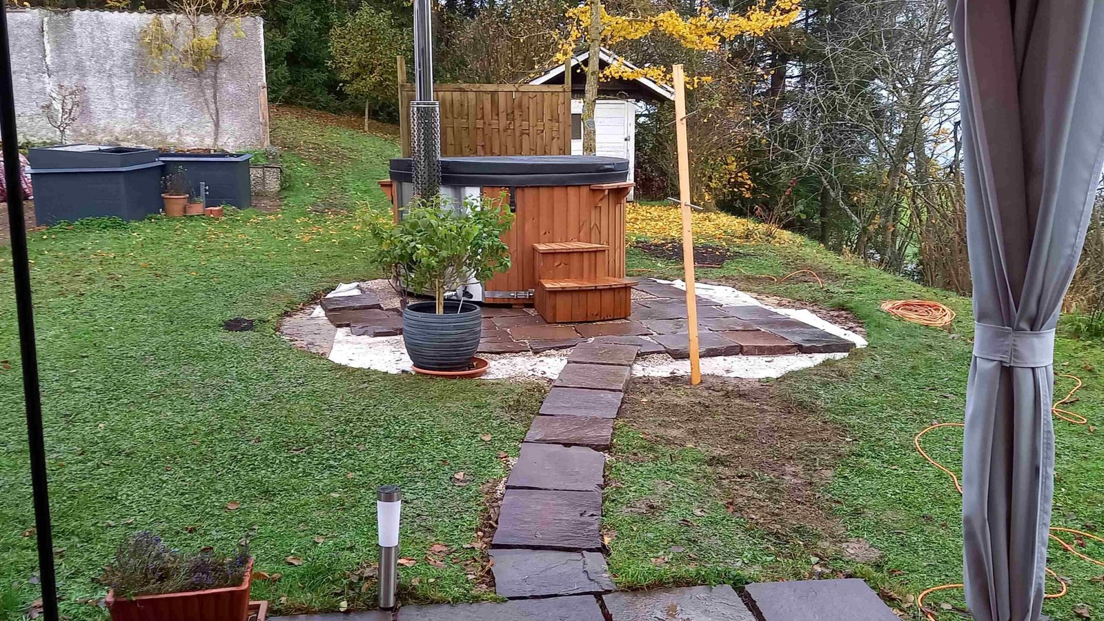 4 Person Hot Tubs 1 Covered round timber-clad hot tub with wooden steps on a paved garden base