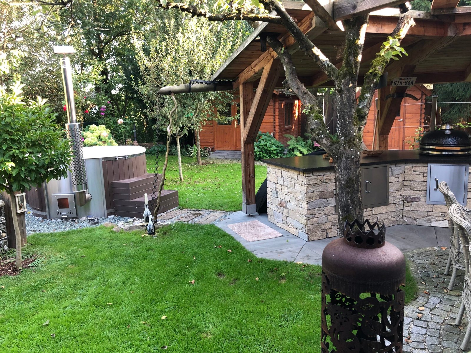 Prices 1 Timber-clad hot tub with a wood-fired stove and steps beside a garden shelter