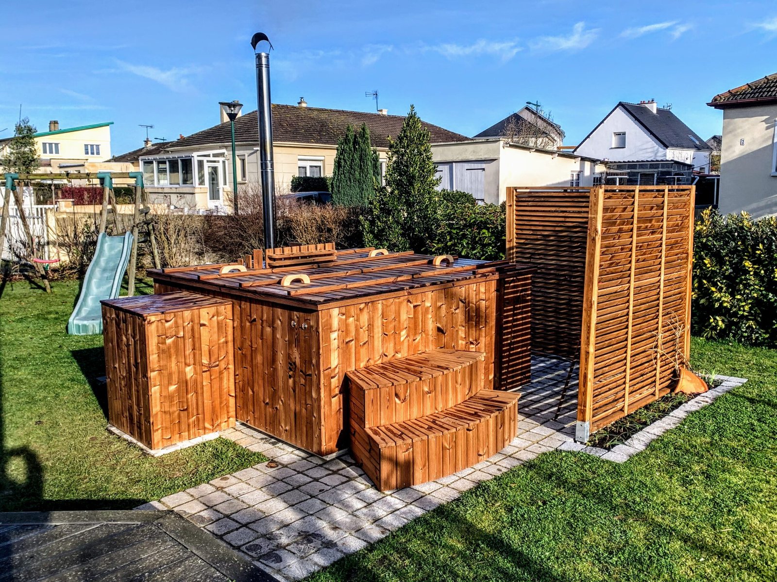 Square Hot Tubs 1 Timber-clad straight-sided hot tub with a wooden cover, steps and a garden privacy screen