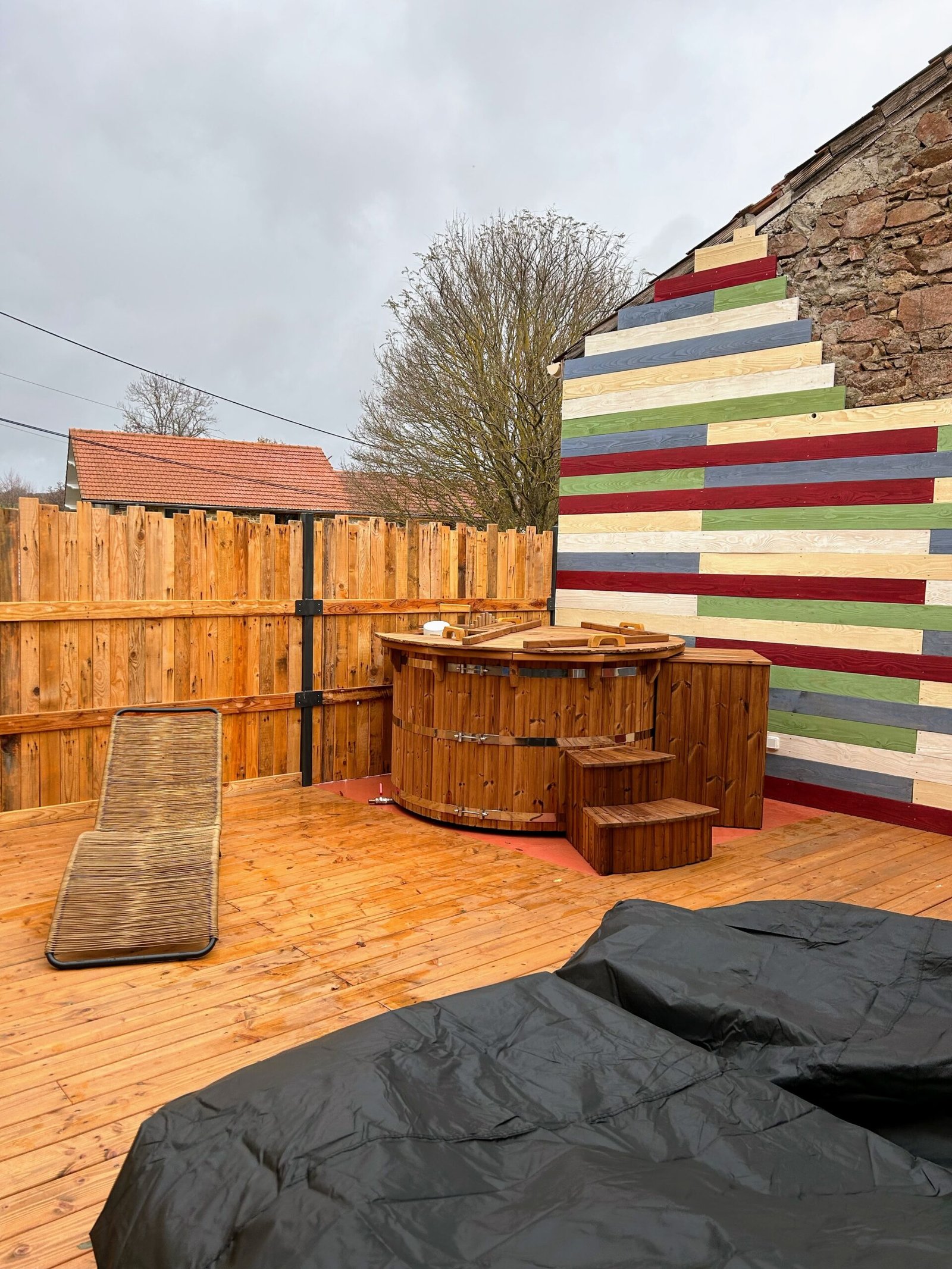 Barrel Hot Tubs 1 Upright timber hot tub with three metal bands, a wooden cover and access steps on decking