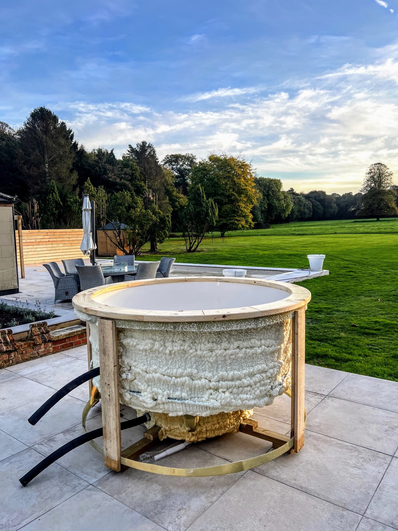Mobile Hot Tubs on Trailer 1 Empty round white hot-tub shell with exposed insulation, timber support frame and projecting pipe ends on a garden patio