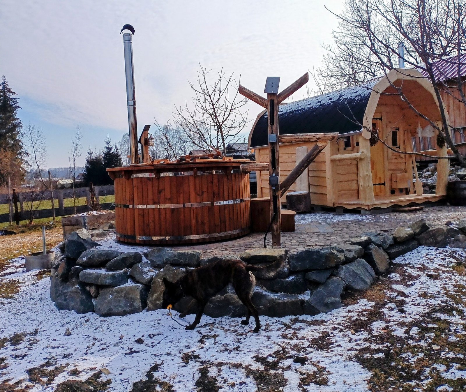 Northern Ireland 1 Covered timber hot tub with a tall flue beside a small sauna on raised paving