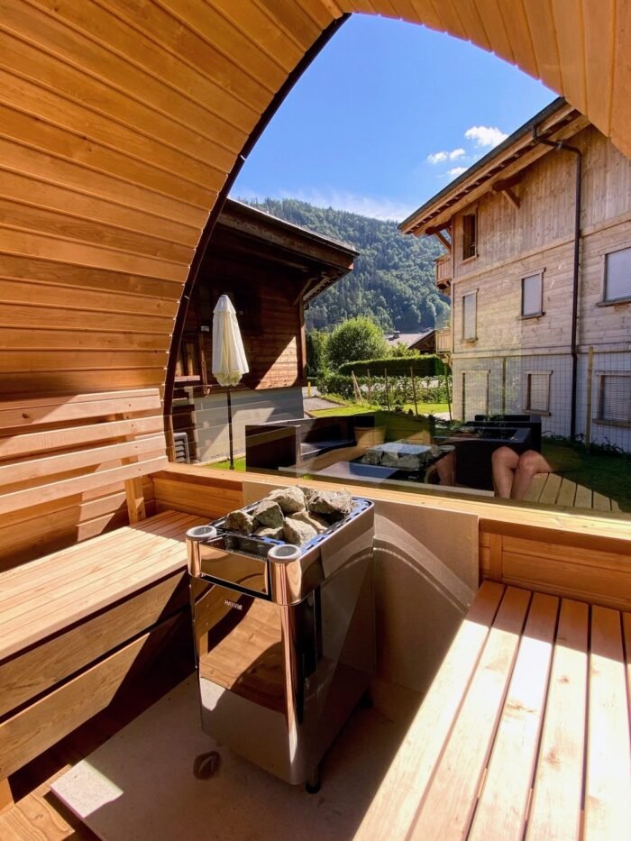 Sauna heater with stones between benches beside a panoramic window