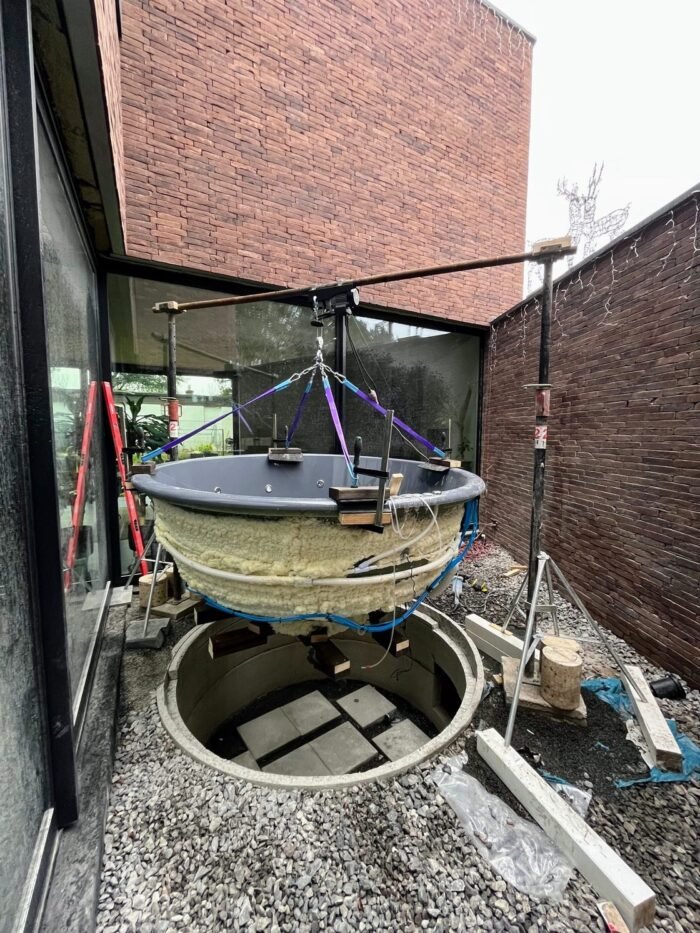 Hot tub shell suspended above a prepared recess
